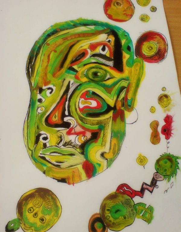 Zelená hlava namalovaná akrylovkami na velkém výkresu, na hlavě je mnoho barevných žlutých a červených detailů, kolem hlavy je spousta barevných kruhů.