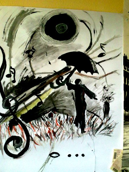 Černobílá malba panáčka s deštníkem, kterému deštník odlétá ve větru, za ním se nachází notová osnova, houslový klíč. Pod ním je celá nota a tři tečky.